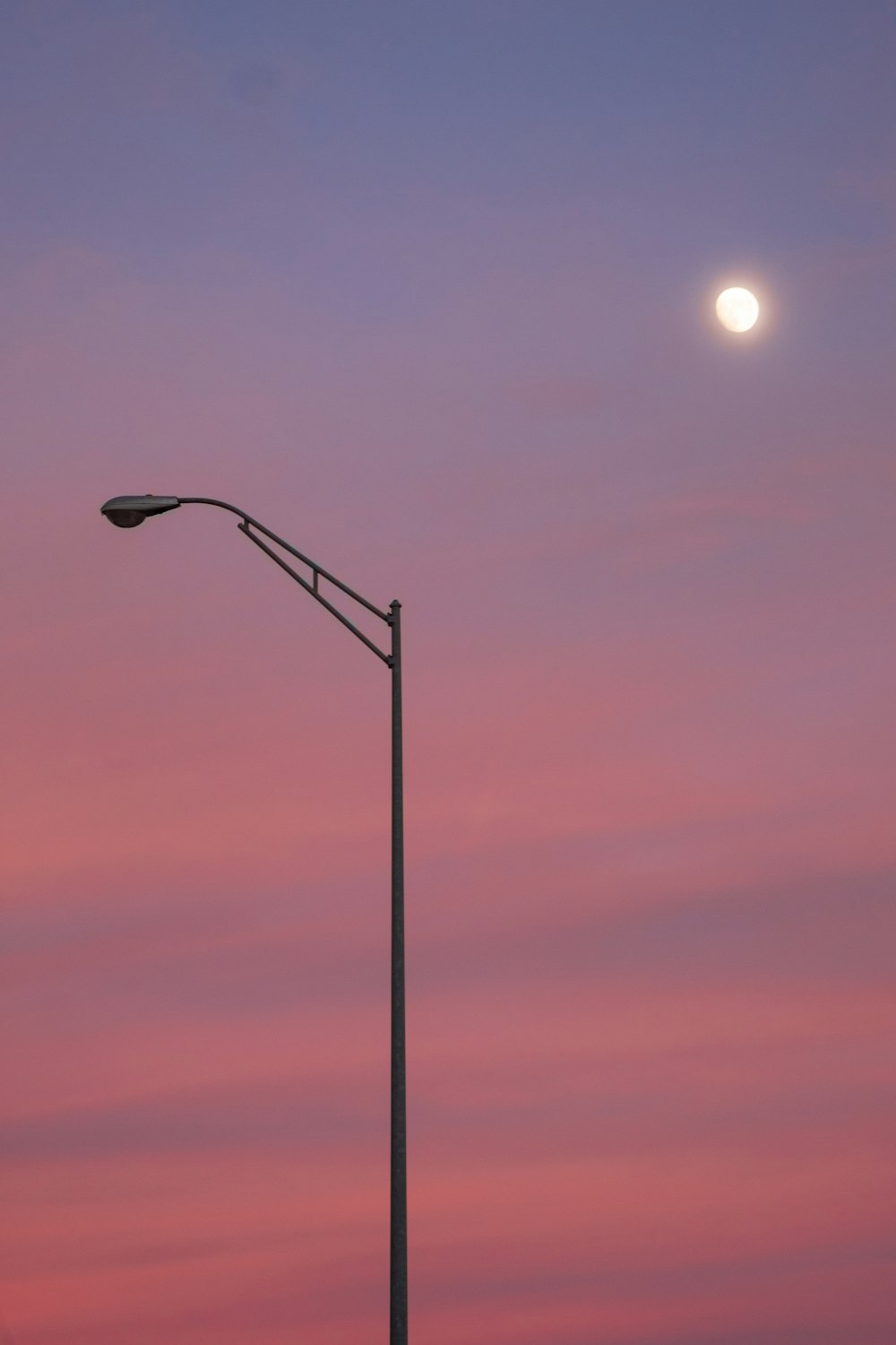 a street light with a full moon in the background