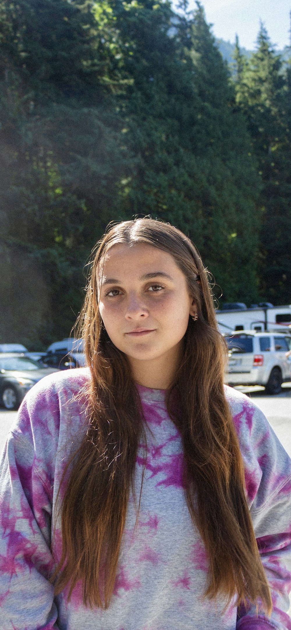 a girl with long hair standing in a parking lot