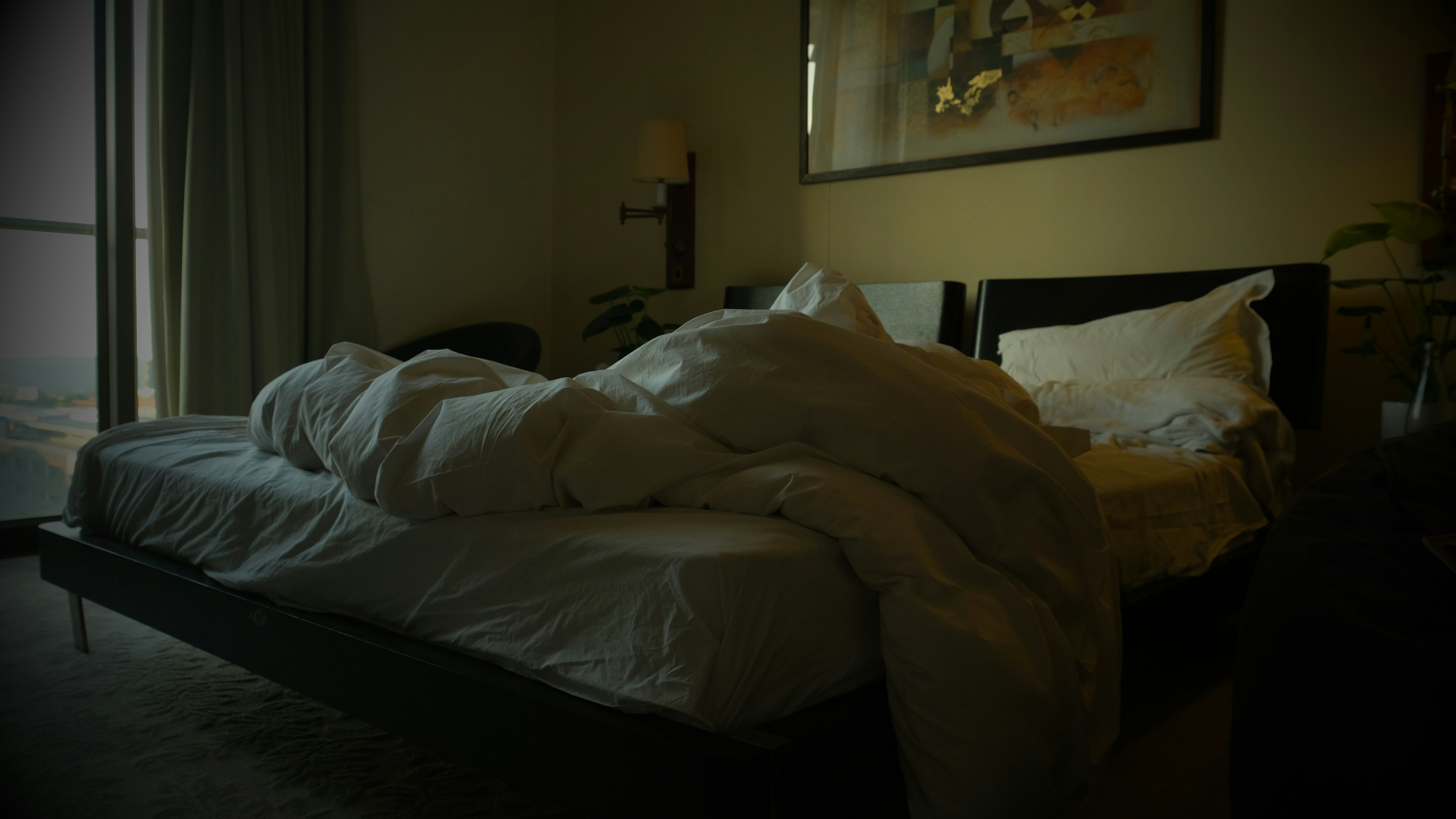 an unmade bed in a dimly lit room, The Michelangelo Towers bedroom