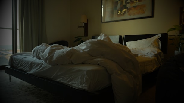 an unmade bed in a dimly lit room