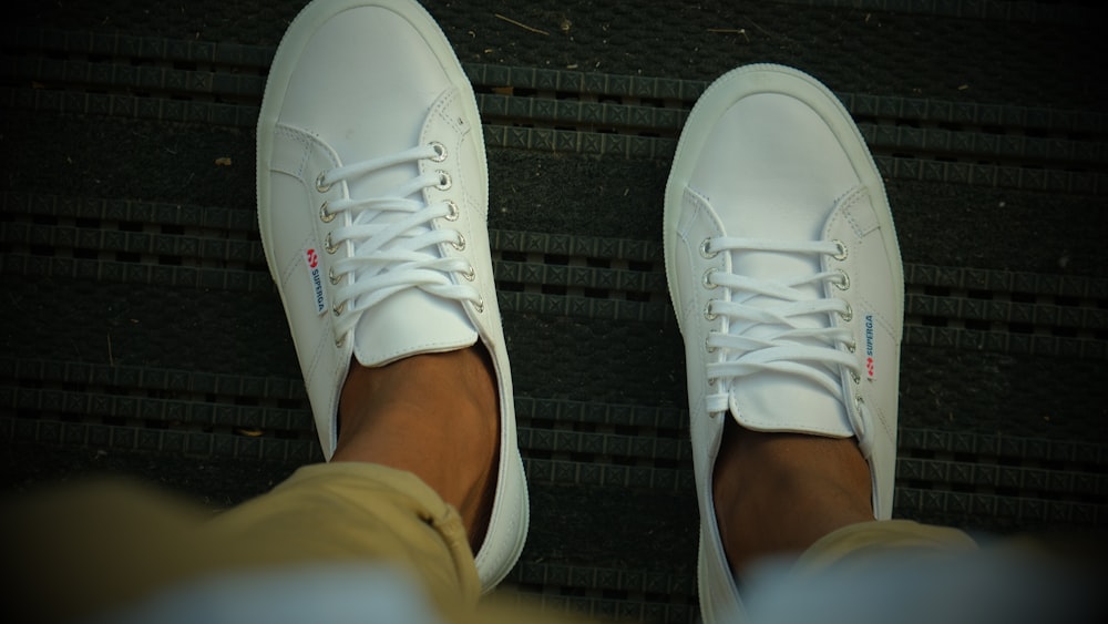 a person wearing white tennis shoes and tan pants