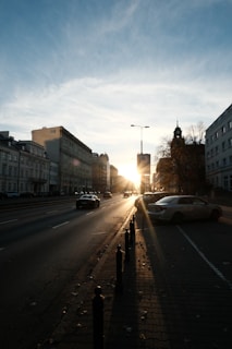 A sunset view of a city street with parked luxury cars.