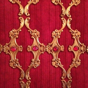 Richly textured artwork featuring deep reds and gold accents.