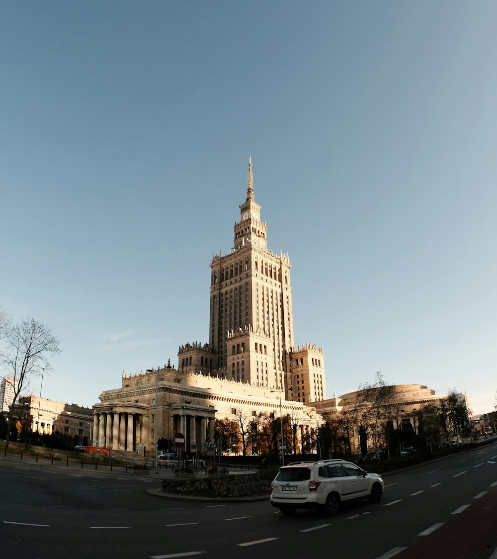 a white car driving down a street next to a tall building