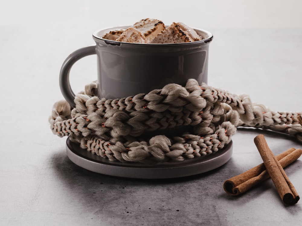 a cup of coffee and cinnamon sticks on a table
