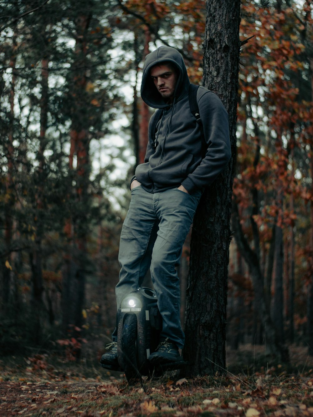 a man leaning against a tree in the woods