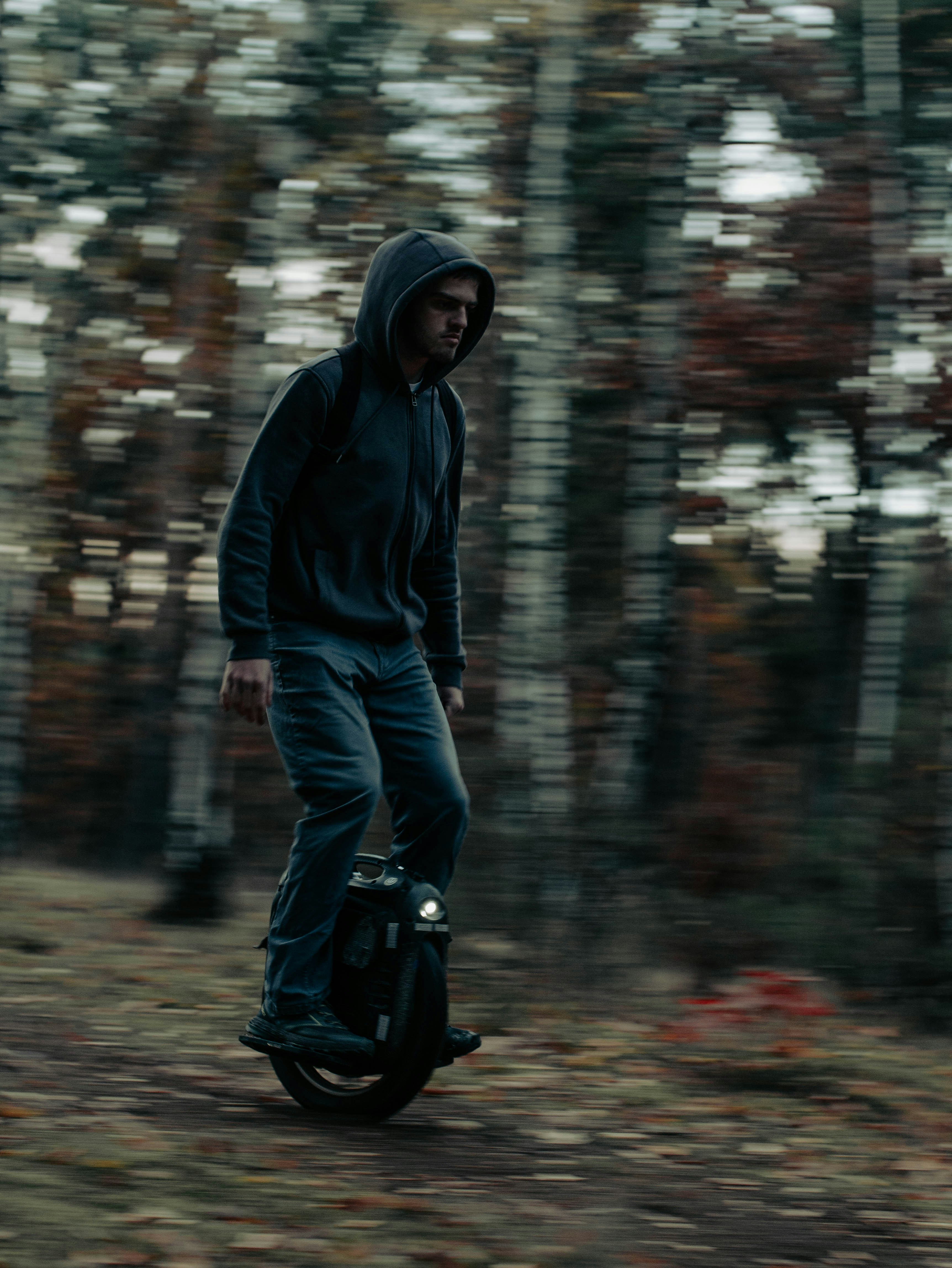 ein Mann, der mit einem Roller durch einen Wald fährt