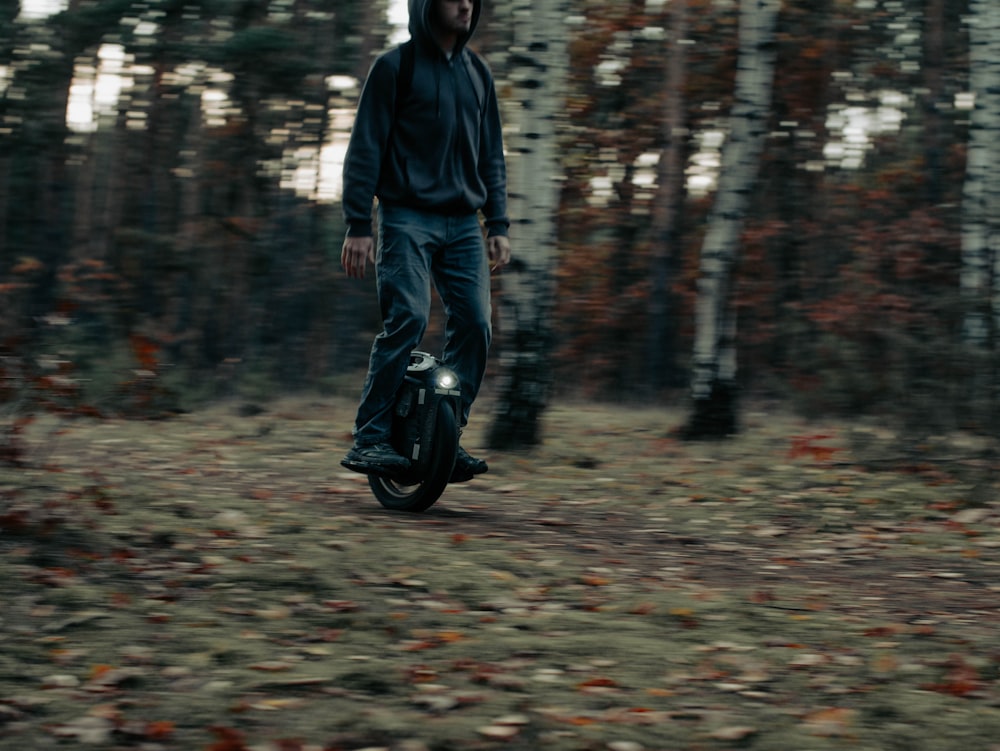 a man riding a motorcycle through a forest