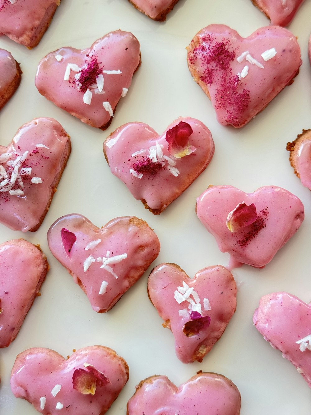 Pasticcini a forma di cuore con glassa rosa e confettini bianchi