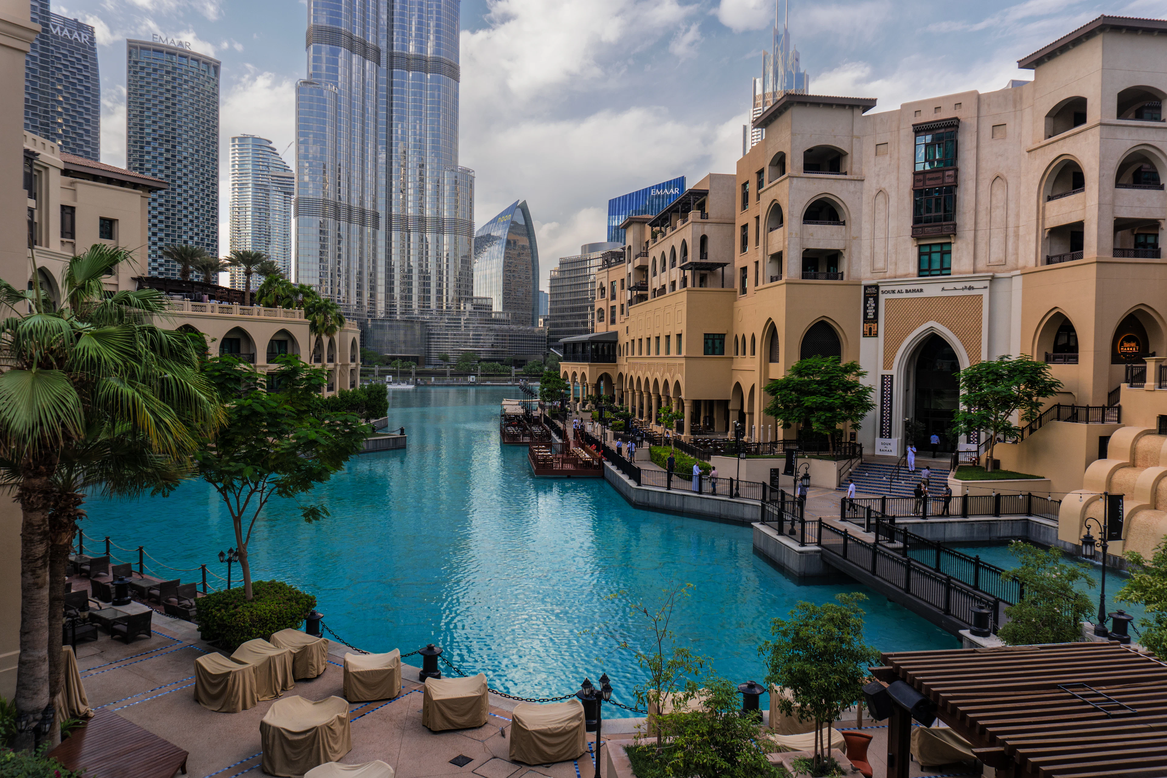 Low-rise buildings around a pool with the Burj Khalifa behind