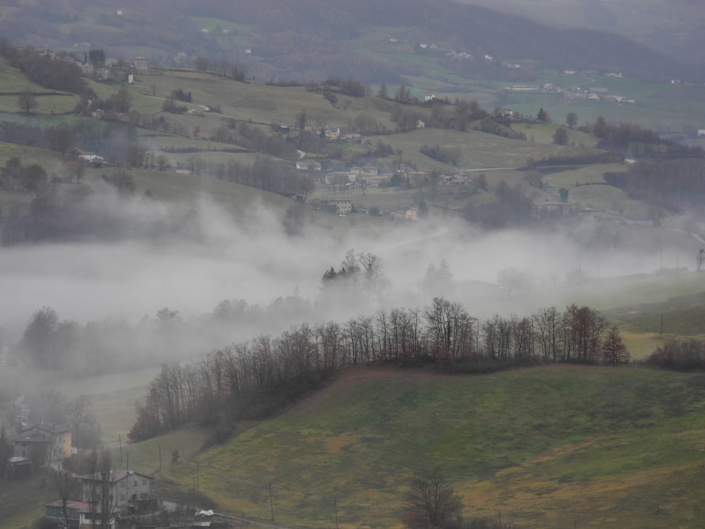 a foggy valley with a small town in the distance