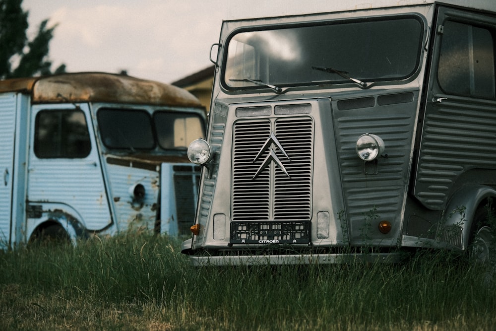 two old trucks sitting in a grassy field