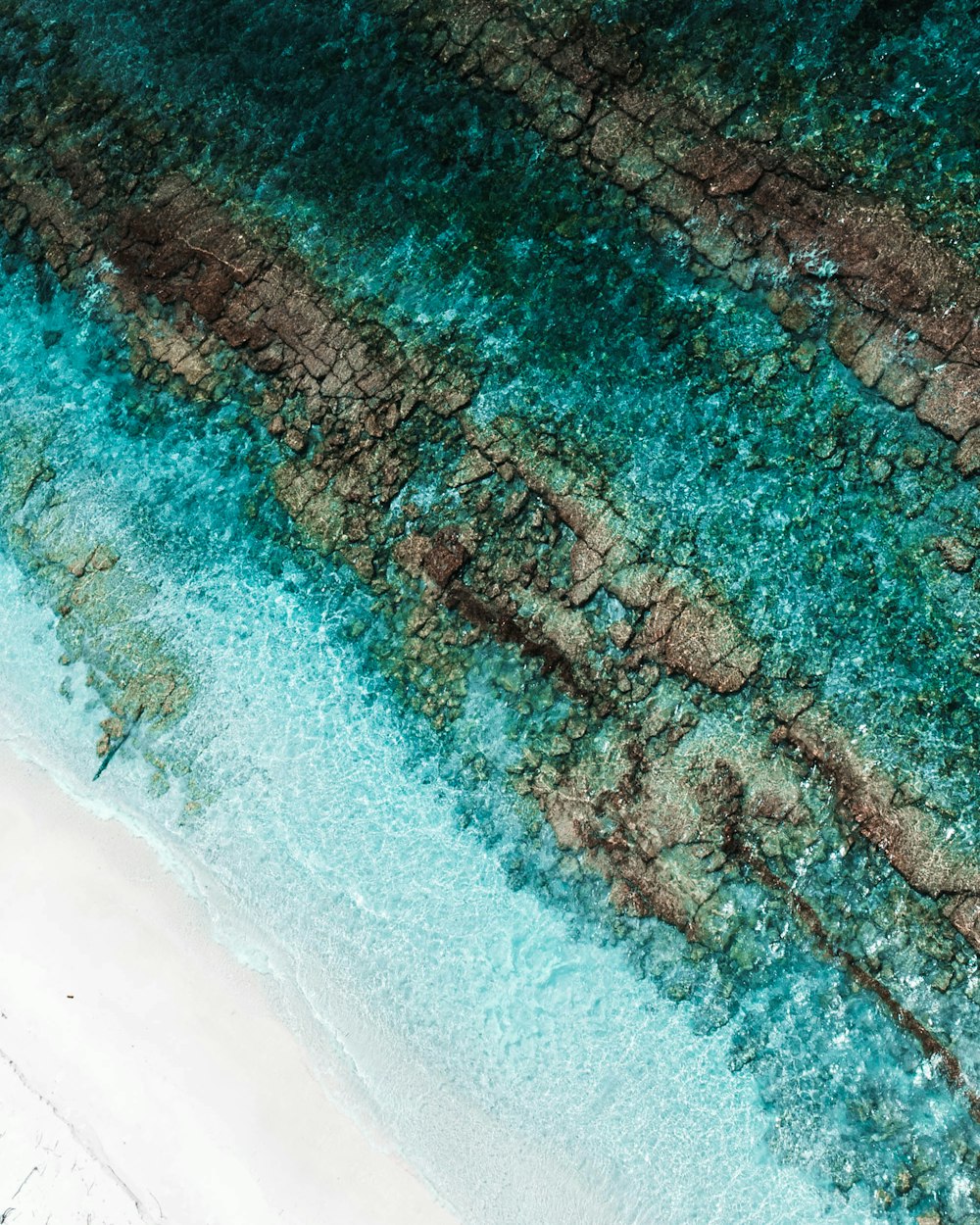 an aerial view of a sandy beach and turquoise water