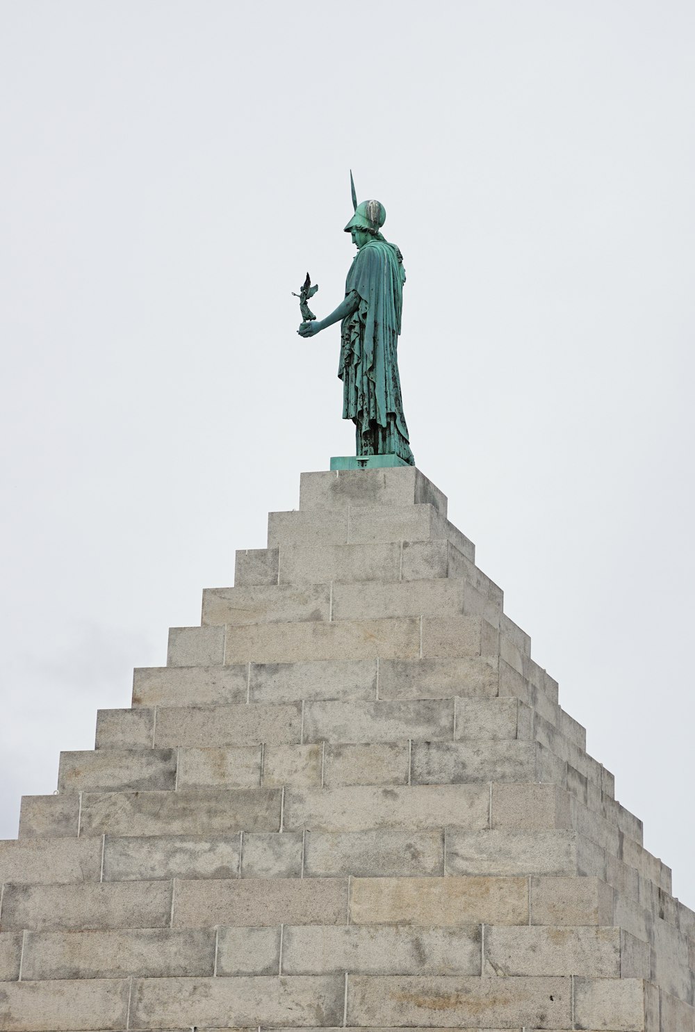 una estatua de un hombre sosteniendo un pájaro en la parte superior de un edificio