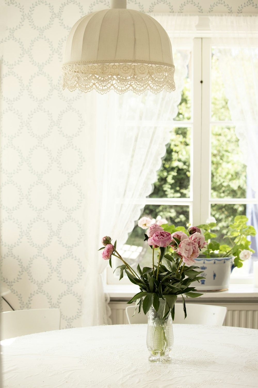 a vase of flowers on a table in front of a window