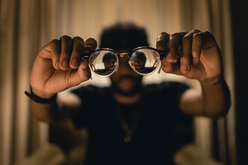 a man holding up a pair of glasses in front of his face