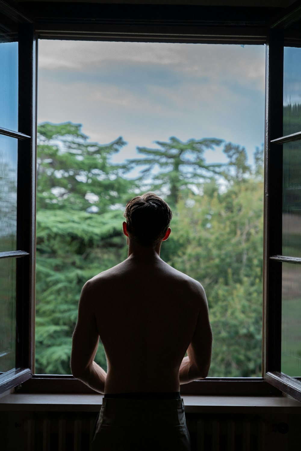 a man looking out of a window at a forest