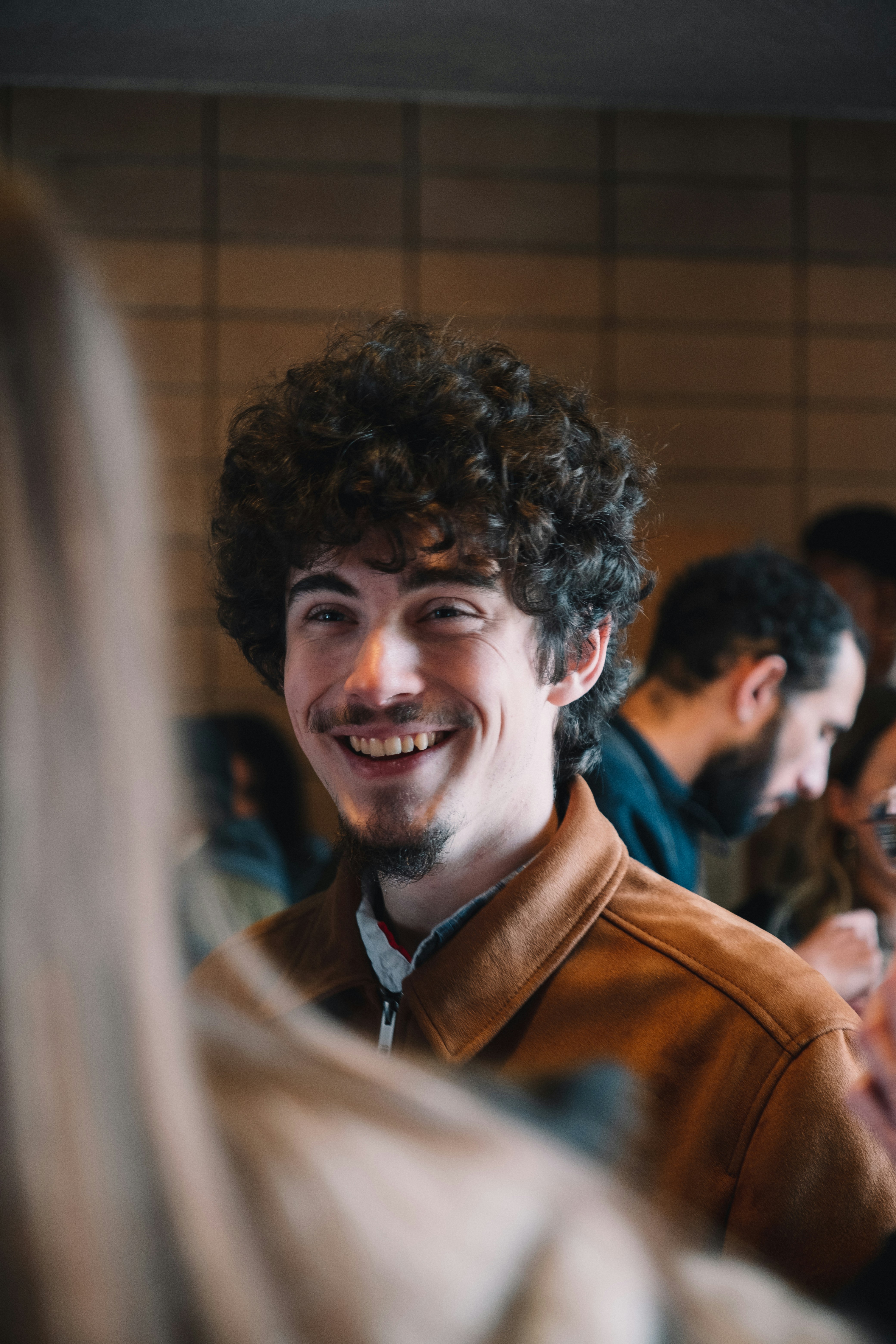 um homem de cabelos cacheados sorrindo para a câmera
