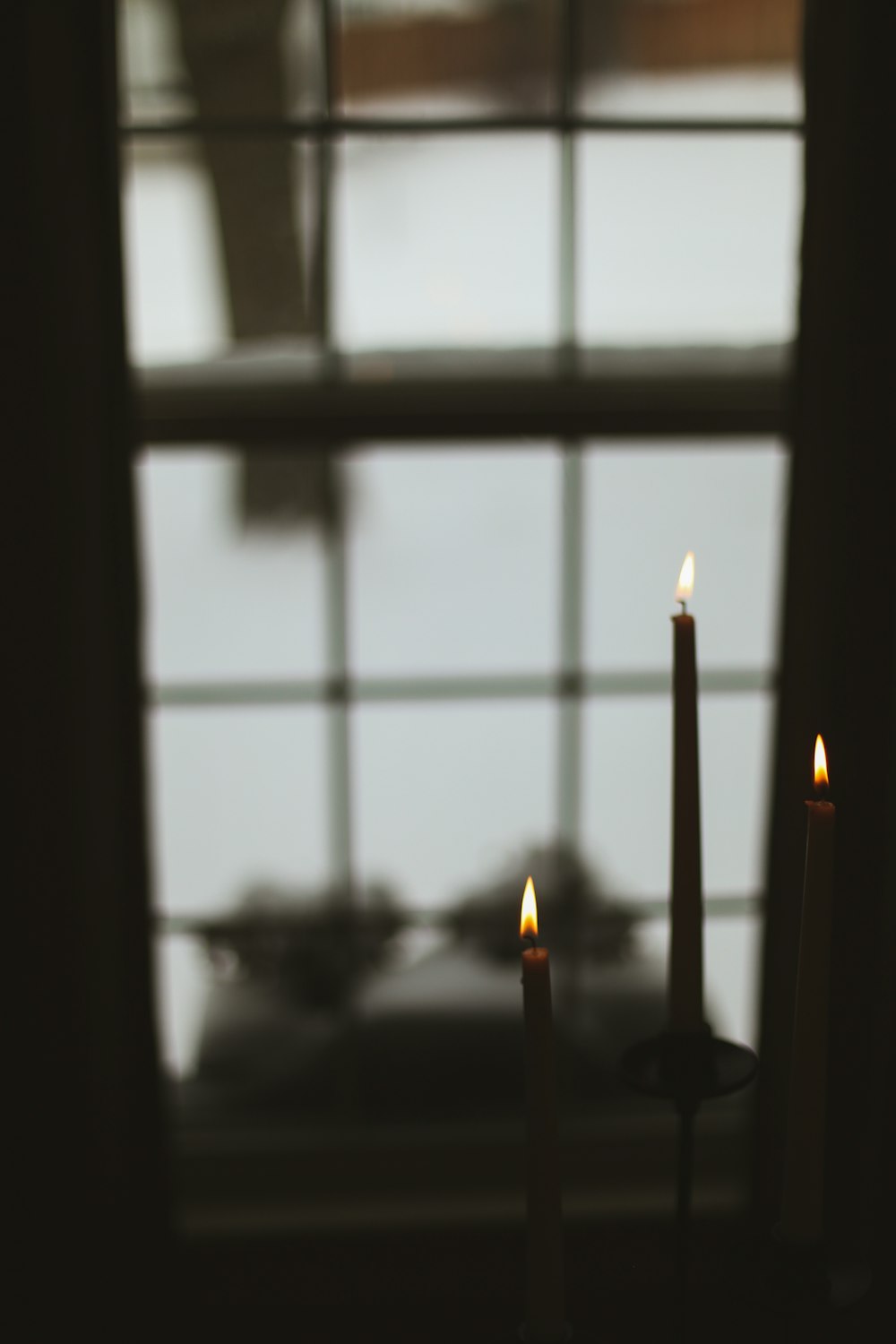 three candles are lit in front of a window