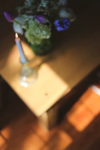 Softly lit candle on a wooden table surrounded by delicate dried flowers