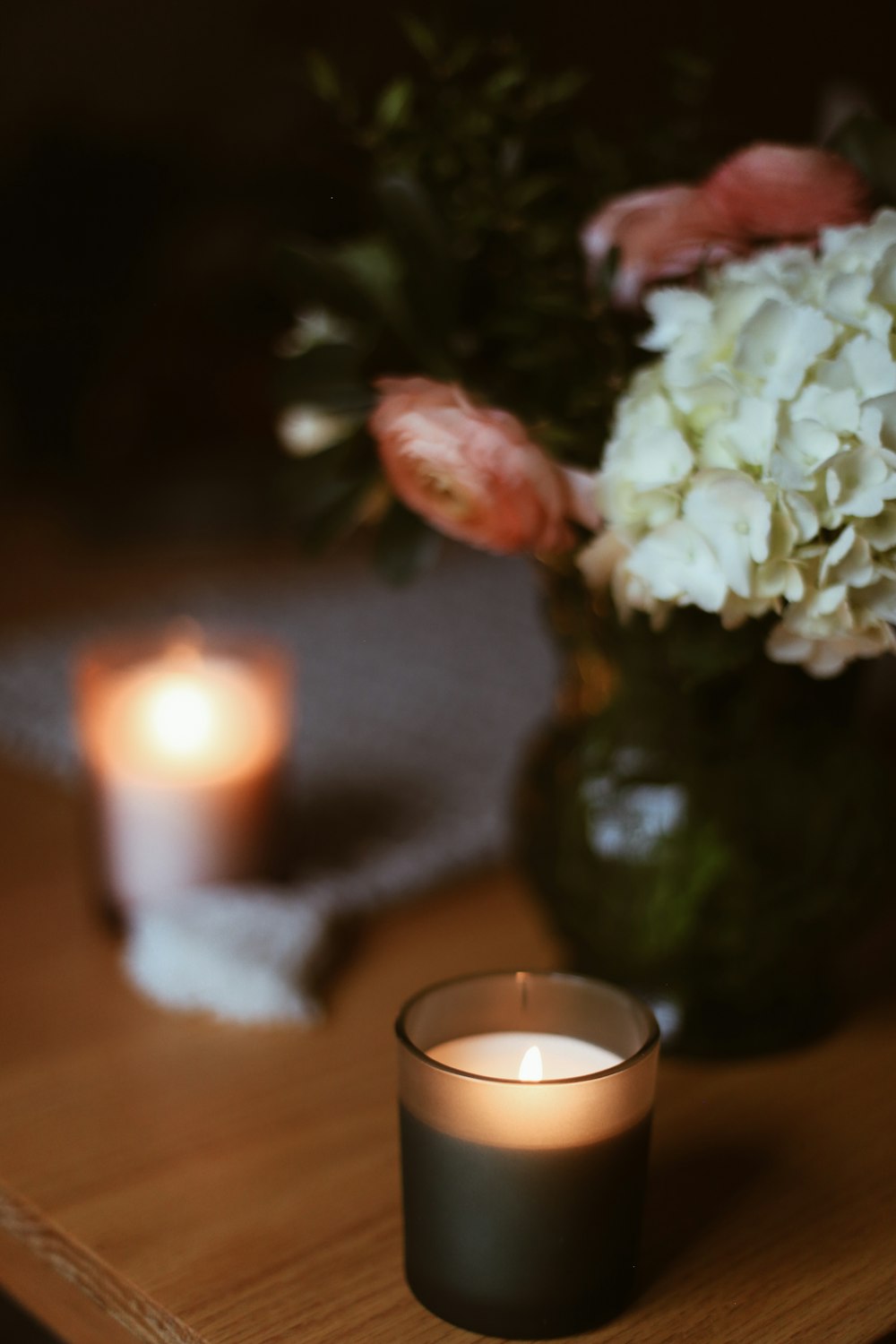 a vase with flowers and a lit candle on a table