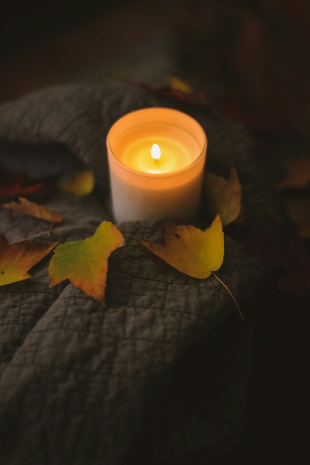 a lit candle sitting on top of a blanket