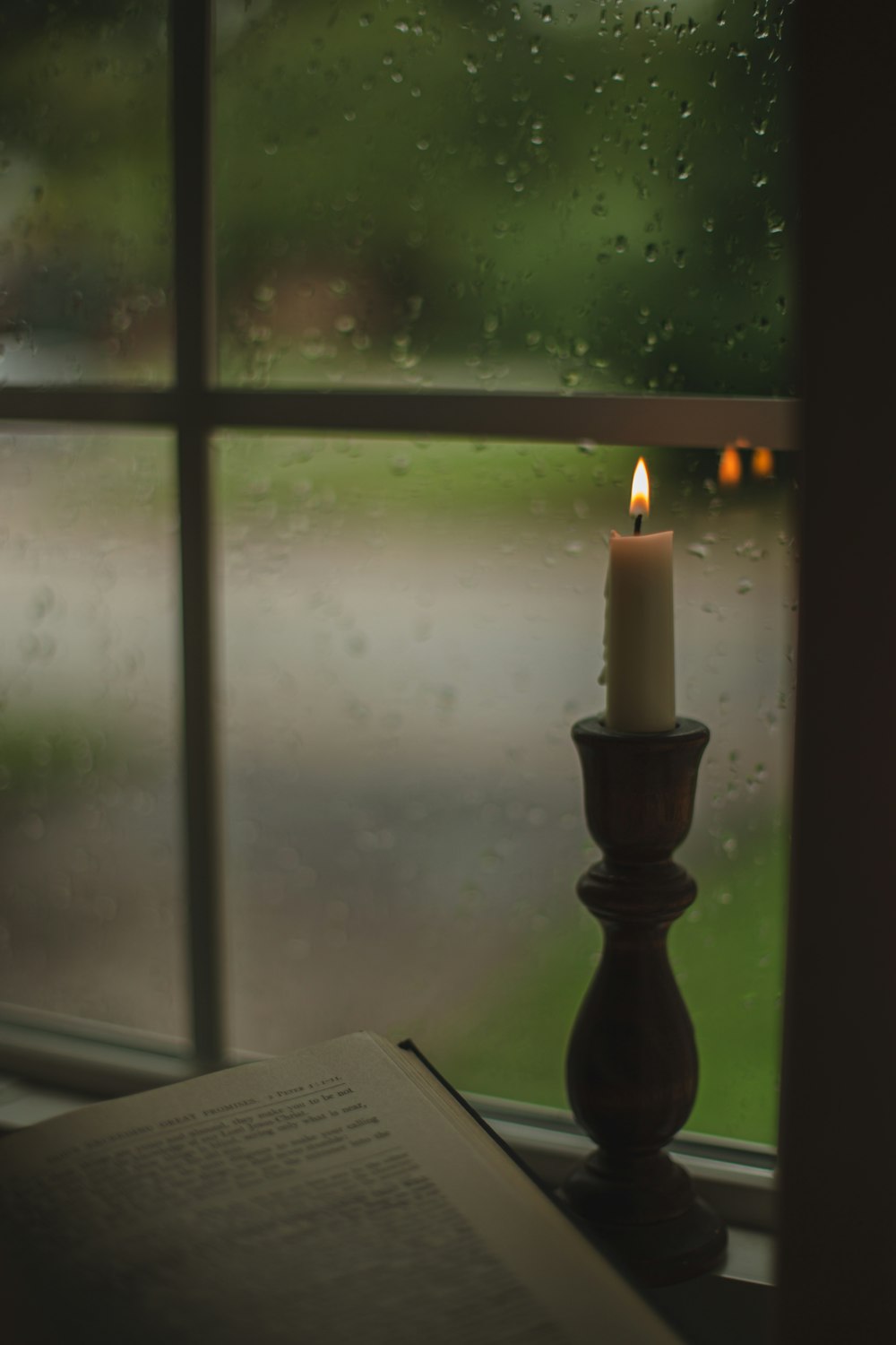 a candle sitting on top of a window sill next to a book