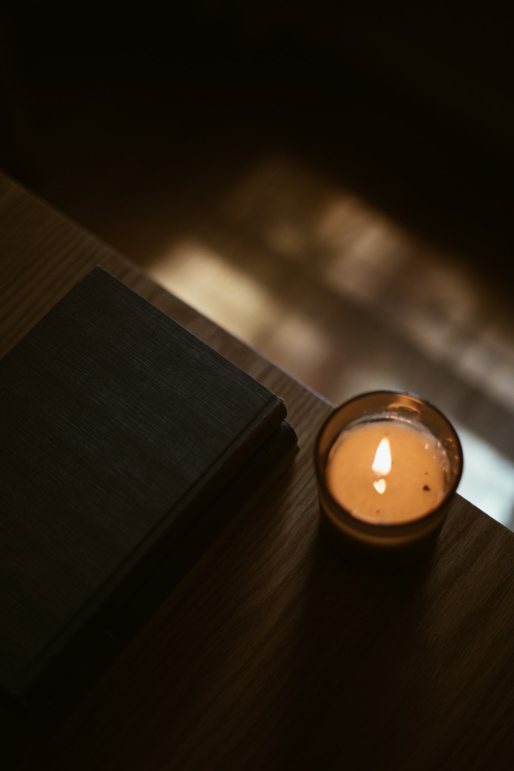 eine brennende Kerze, die auf einem Holztisch steht