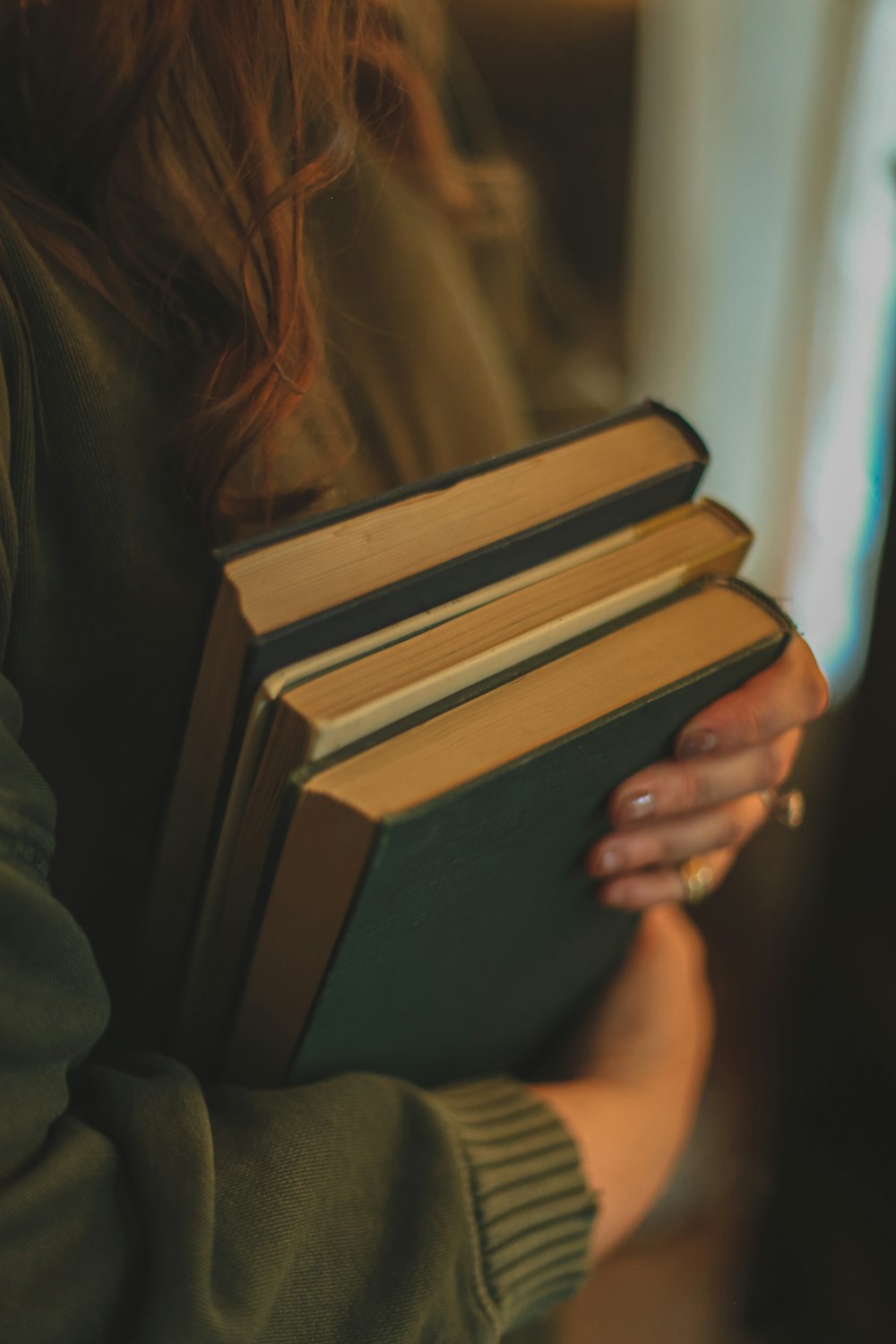 a woman holding a stack of books in her hands