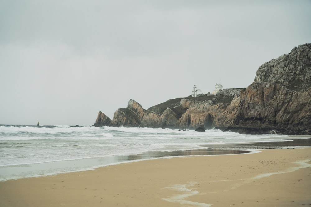 a sandy beach next to a large rock formation