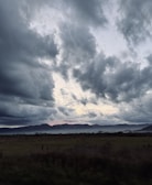 A cinematic landscape with a dark, cloudy sky and subtle light breaking through, emphasizing depth.