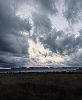 A cinematic landscape with a dark, cloudy sky and subtle light breaking through, emphasizing depth.