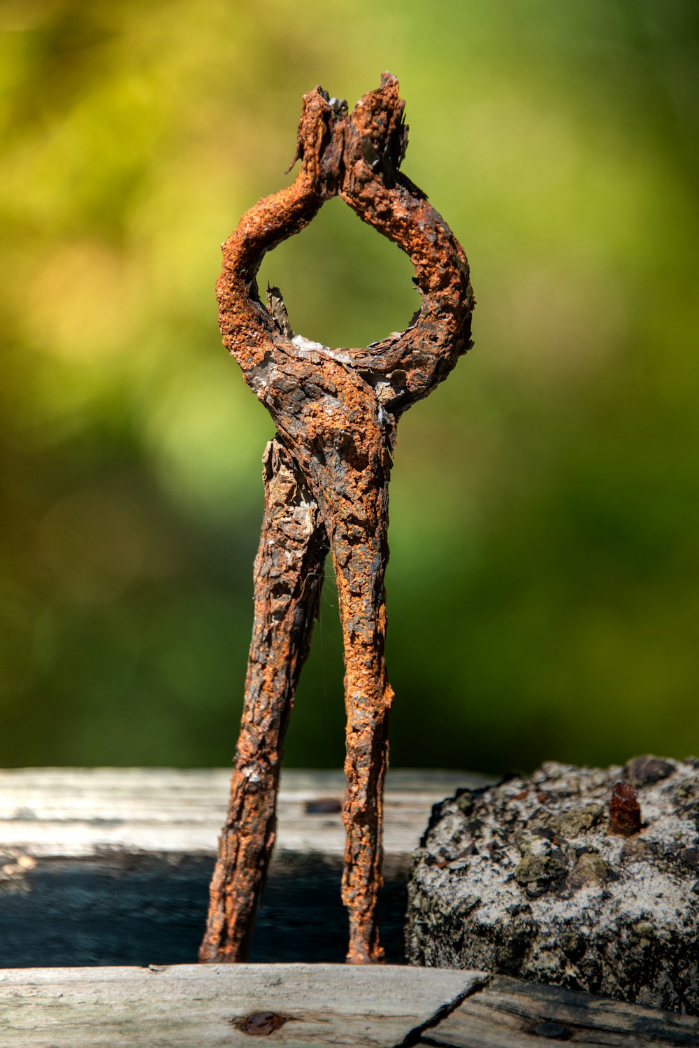 a rusted metal figure standing on a wooden surface