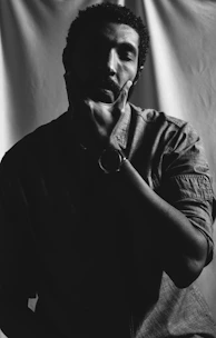 a black and white photo of a man holding his hand to his face