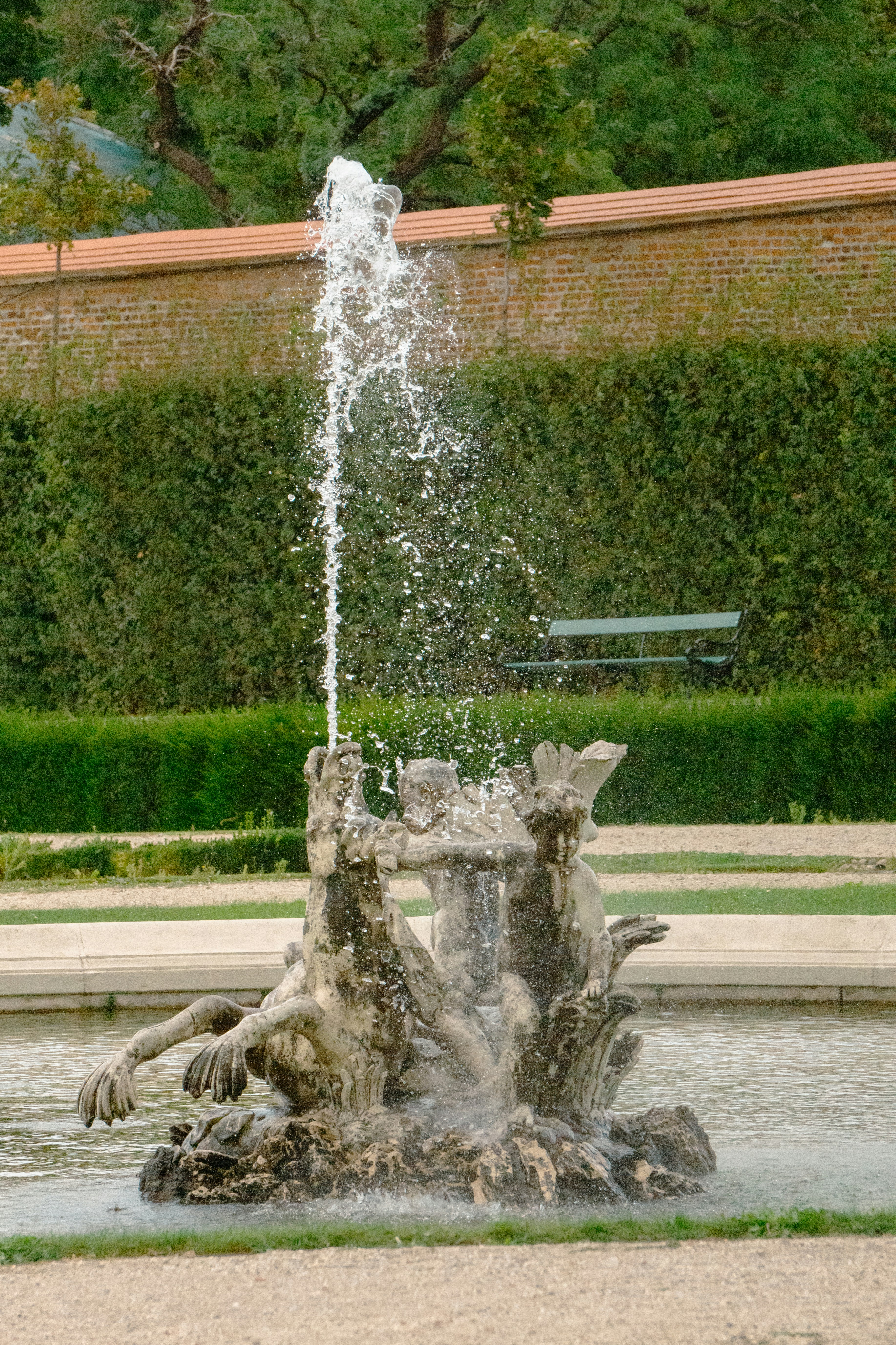 a fountain spewing water into a pond in a park