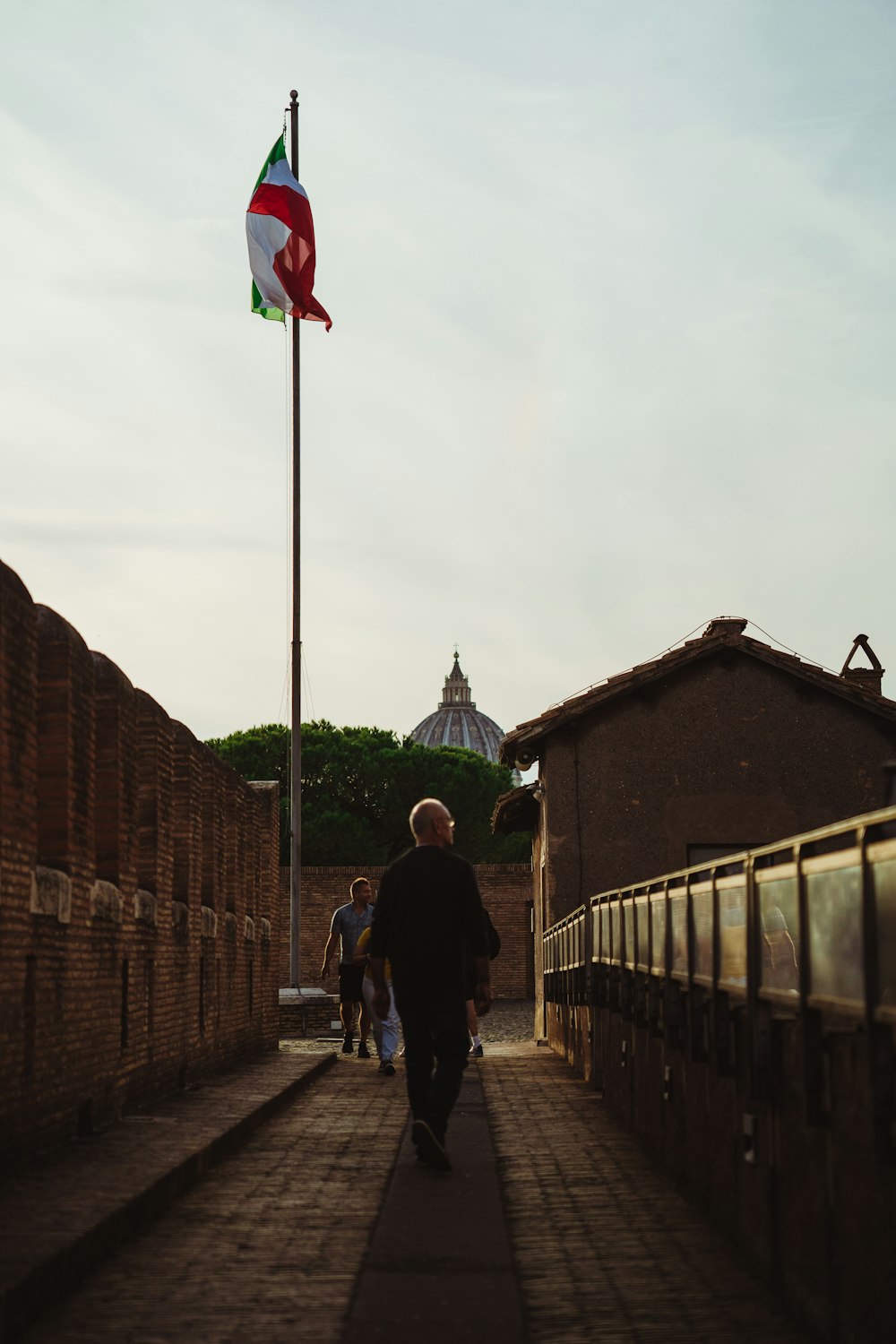 a man walking down a sidewalk next to a flag