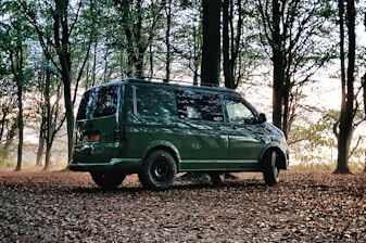 a green van is parked in the woods