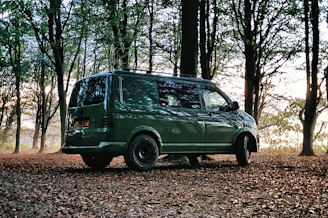 a green van is parked in the woods