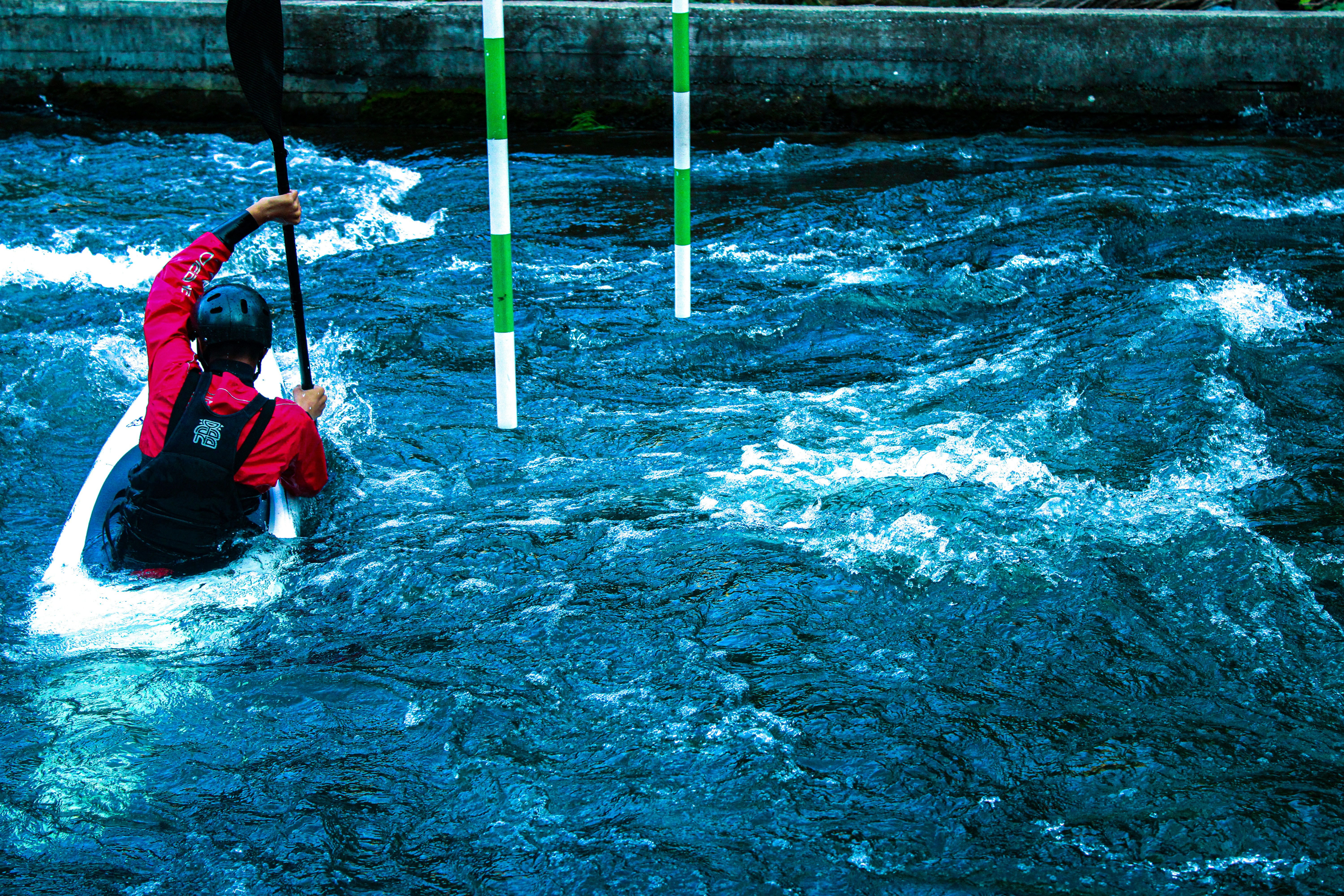 Un hombre con una chaqueta roja remando en una canoa río abajo