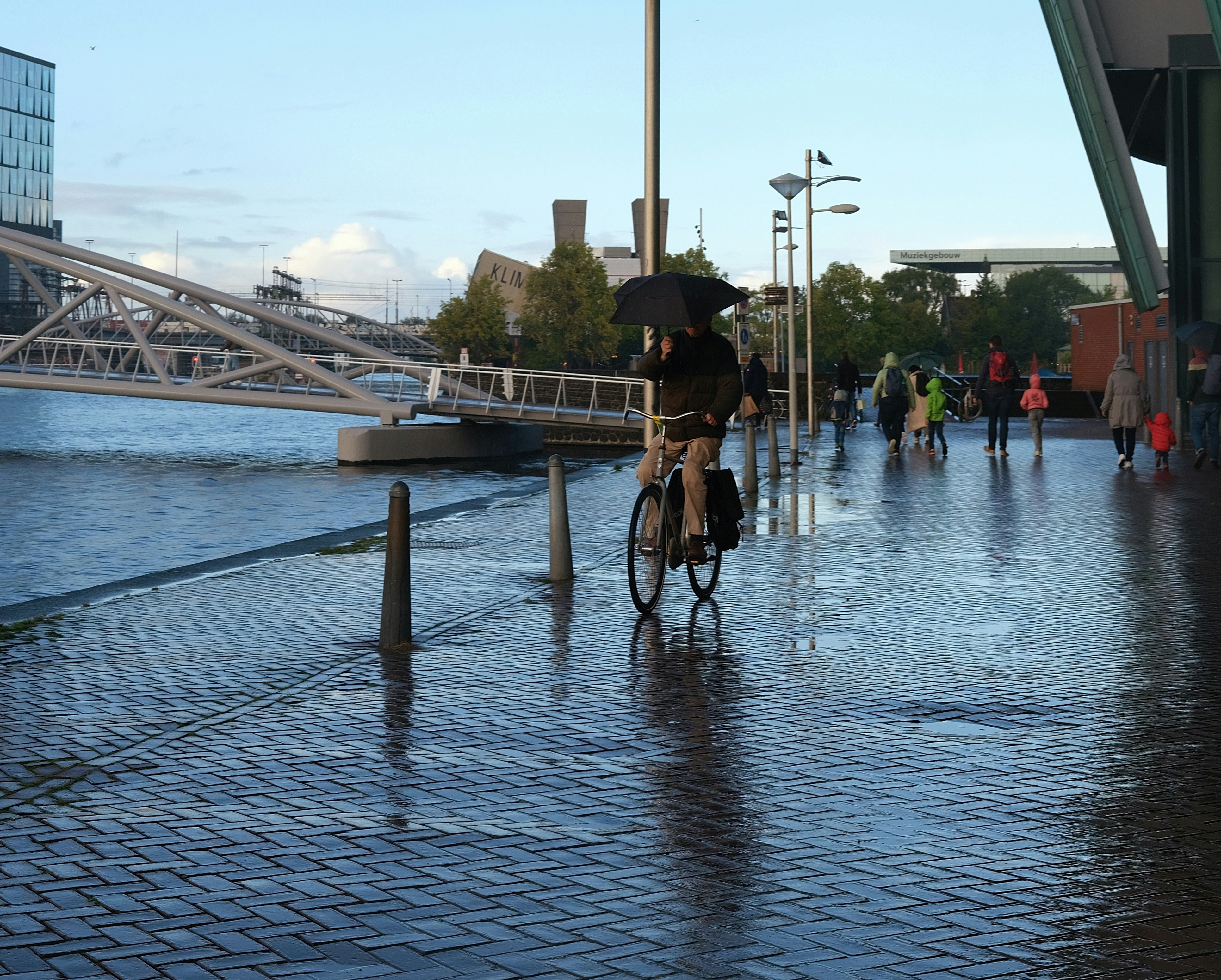 a man riding a bike down a wet sidewalk