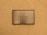 A metallic plaque with a wooden frame mounted on a textured beige wall. The plaque has the text 'The Luxury Collection' engraved in black, centered on its surface.