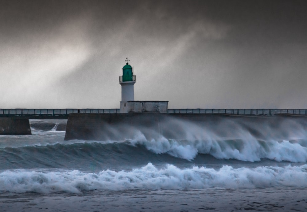 a lighthouse on a pier with waves crashing in front of it