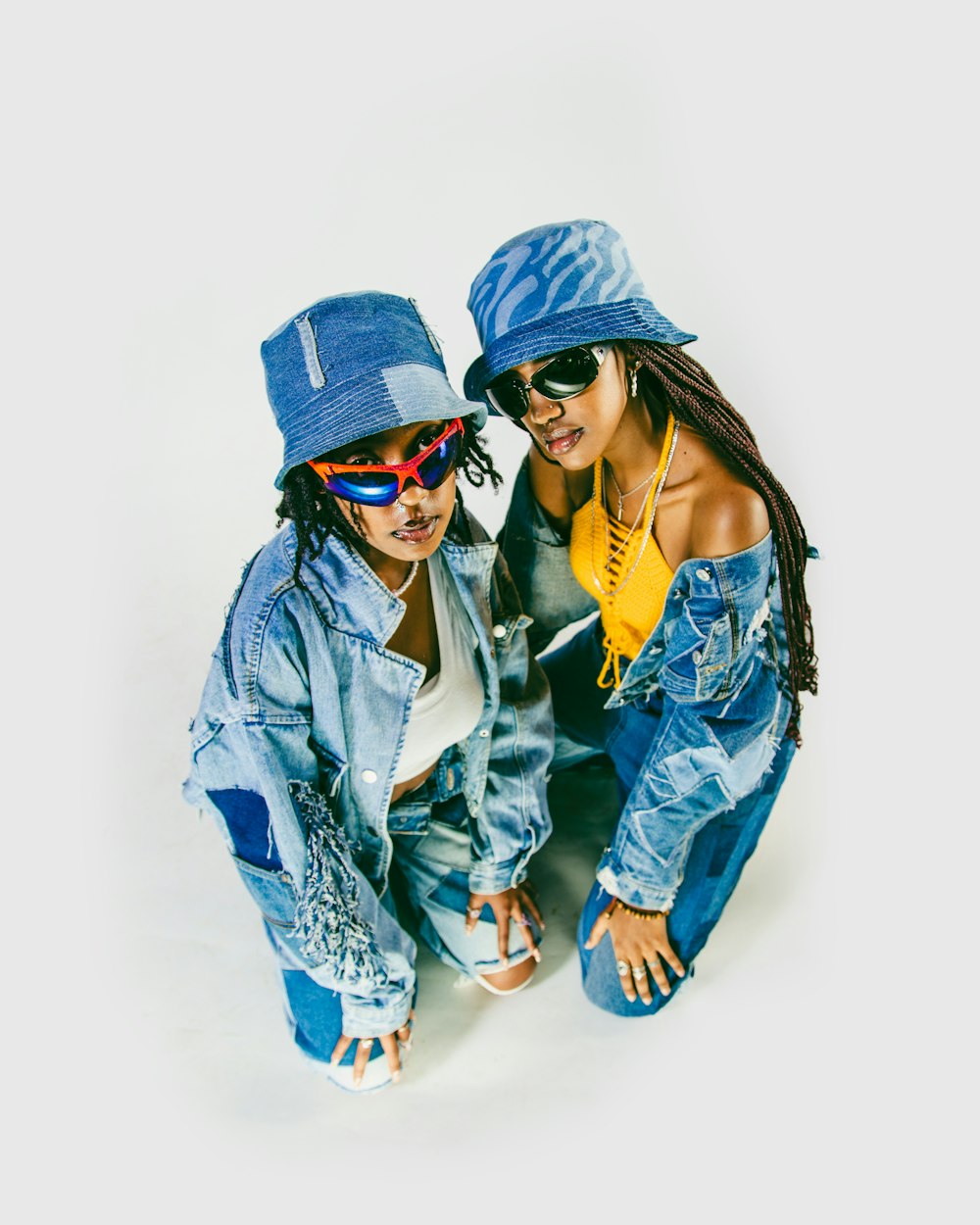 two young women wearing hats and jeans posing for a picture