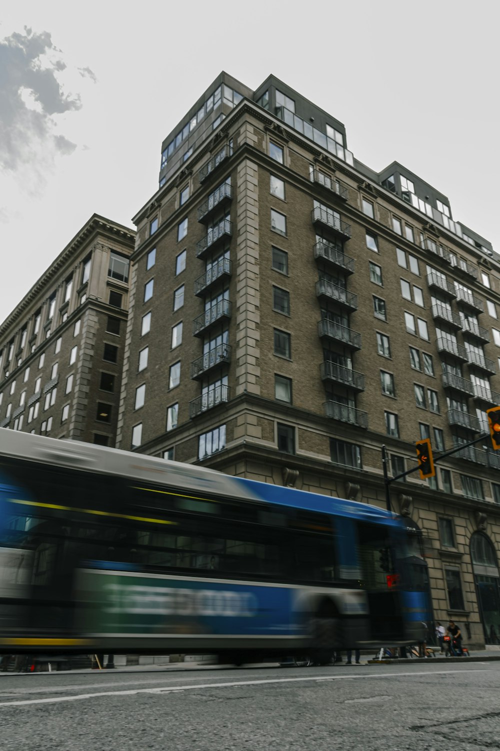 a blue bus driving down a street next to a tall building