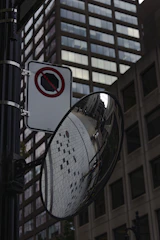 A convex mirror mounted at a sharp corner in a parking lot reflecting incoming cars.