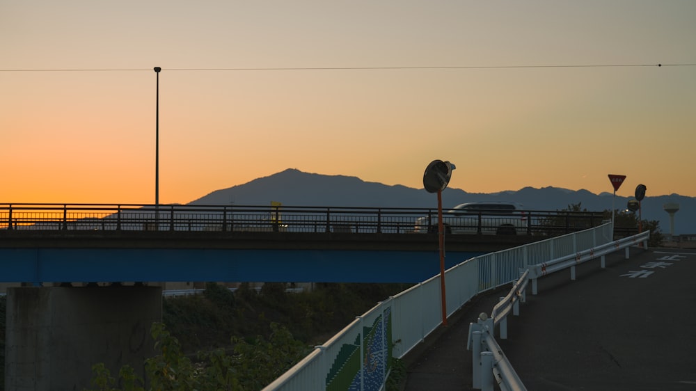 the sun is setting on a bridge over a highway