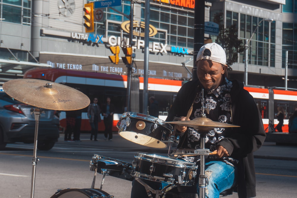 a man sitting on the side of a road next to a drum set
