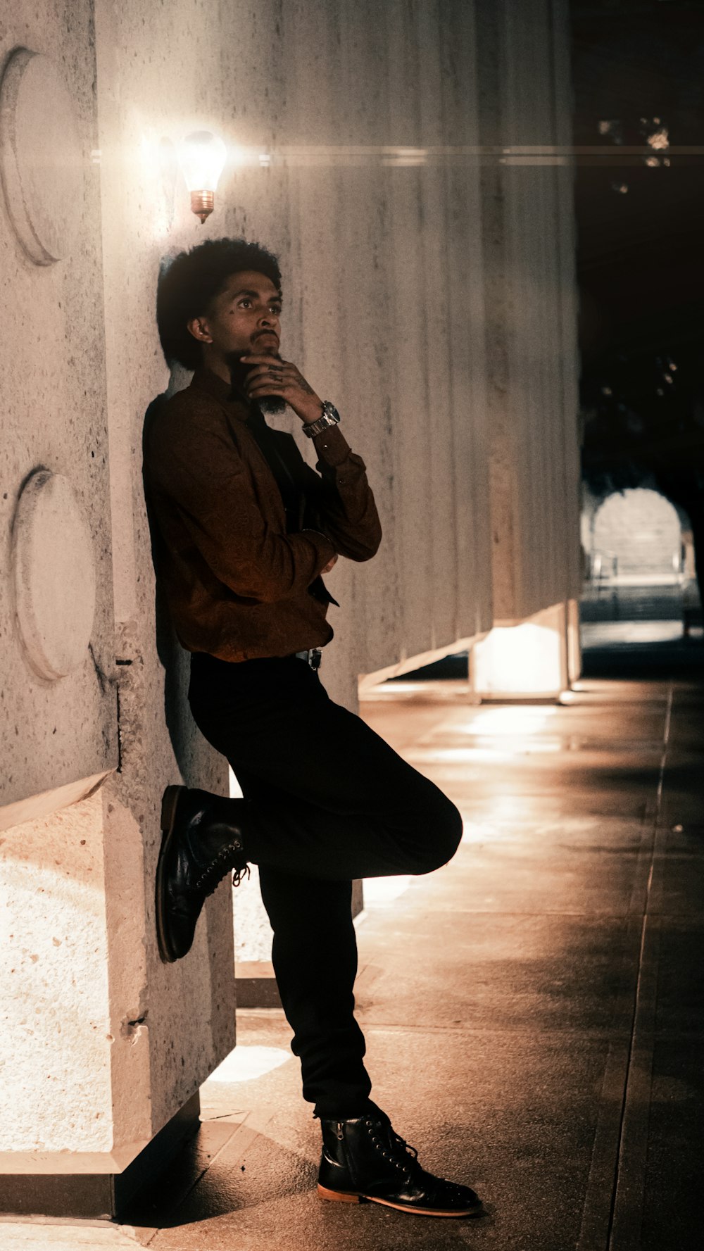 a man leaning against a wall while smoking a cigarette