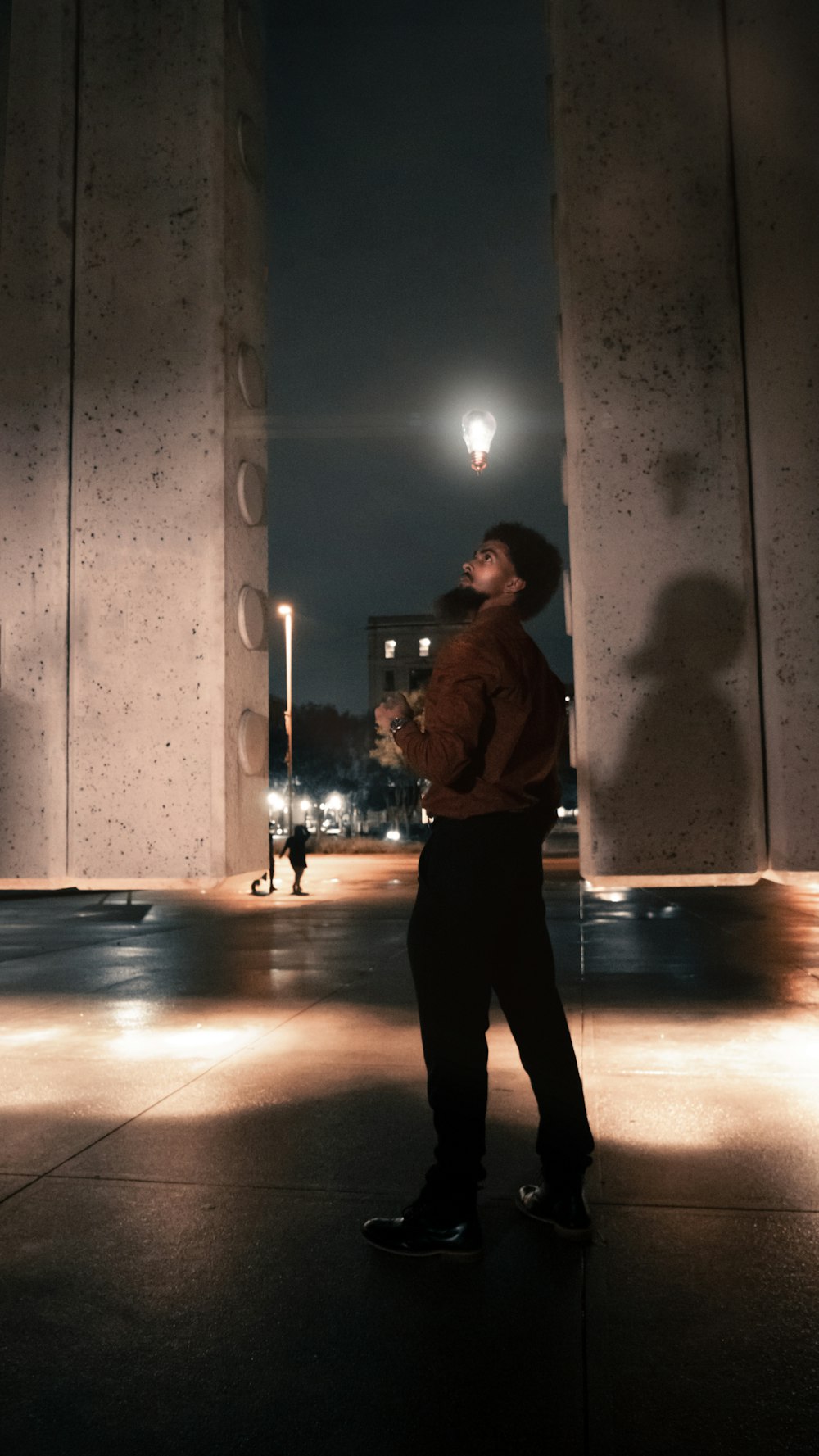 a man standing in the middle of a walkway at night