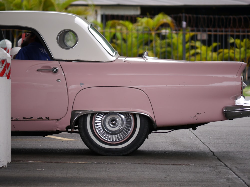 a pink and white car parked on the side of the road